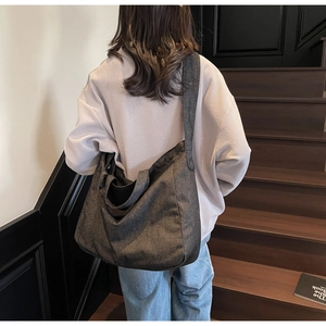 Detail of dark grey minimalist canvas tote bag carried by model on wooden stairs