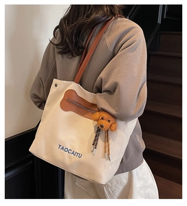 Detalle del bolso tote de lona con bolsillo marrón en forma de hueso y dije de perro