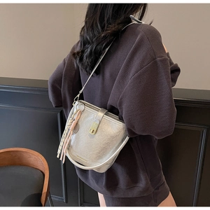 Sac seau argenté avec fermoir doré et détail de gland tressé sur cuir texturé