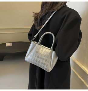 Detail shot of a silver woven bucket bag featuring a quilted lattice texture and round handle