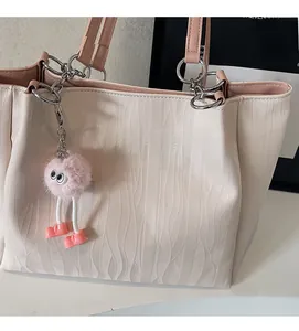 Close-up of cream tote bag with pink handles, wave texture, and cute plush charm detail