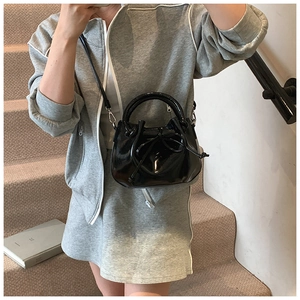 Detail of black wax leather bucket bag featuring a drawstring bow and silver hardware