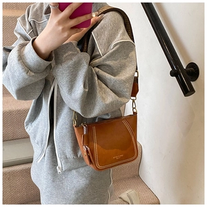 Close-up of brown leather crossbody bag with metal rivets and ethnic woven wide strap