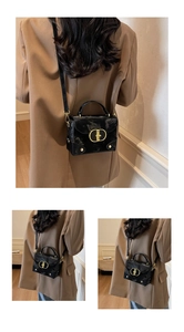 Detail of glossy black handbag with water ripple texture and golden oval lock buckle
