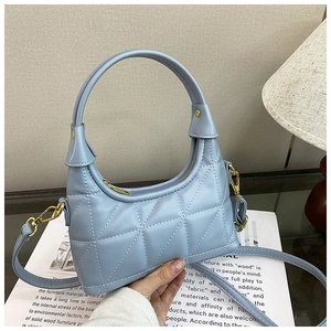 Detail of light blue quilted shoulder bag with gold hardware and removable strap