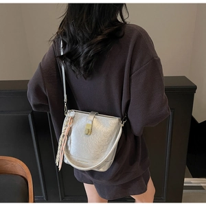 Détail du sac seau argenté avec fermoir doré et foulard en soie sur un mannequin