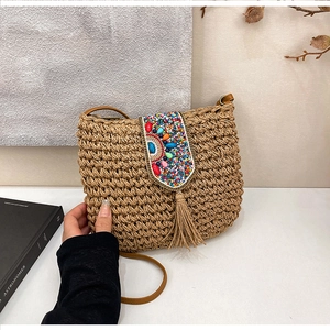 Detail showing bohemian straw bag with colorful bead embroidery and raffia tassels