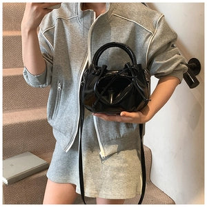 Detail of black wax leather bucket bag with bow drawstring and glossy finish on stairs