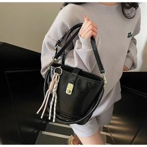 Détail du sac demi-lune noir avec fermoir rotatif doré et pompons en corde colorés