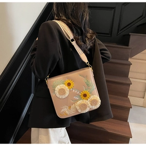 Detailed 3D floral embroidery of sunflowers and daisies on beige leather bucket bag