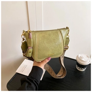Detailed macro view of green lychee leather texture and golden logo on fashion bag