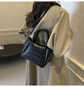 Detail of black quilted leather bucket bag with top handles and adjustable strap on model