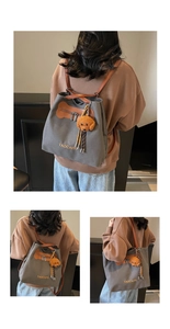 Detalles del bolso de lona gris con correas de cuero y colgante de peluche