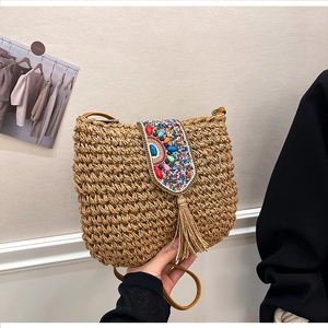 Detail of bohemian straw bag with ethnic beadwork, gold chain trim and long fringes