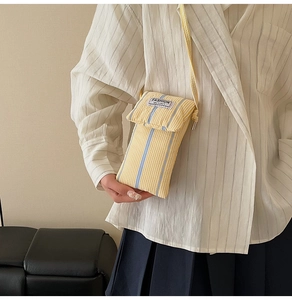 Detail view of the striped canvas crossbody phone bag featuring a Fashion Instinct fabric tag