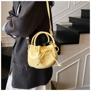 Detail of a bright yellow oil wax leather bucket bag featuring a cute bow and drawstring closure