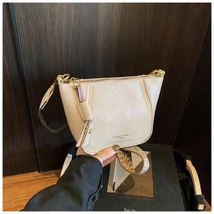 Detail of beige textured leather dumpling bag with woven strap and gold metal hardware