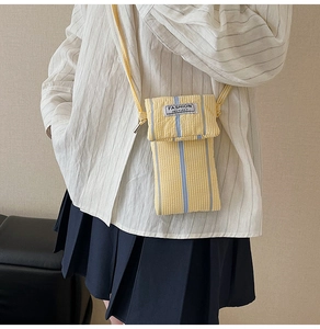 Detailed view of striped mini crossbody bag with a white fashion instinct fabric label