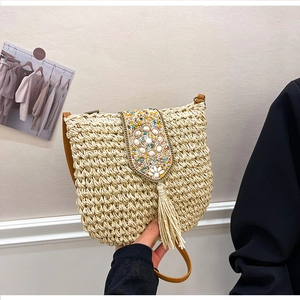 Detail of straw crossbody bag with floral beadwork, sequins and long tassels