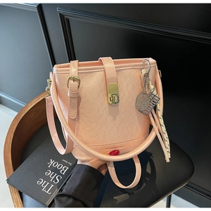 Détail du sac seau rose en cuir grainé avec fermoir doré et décoration de foulard chic