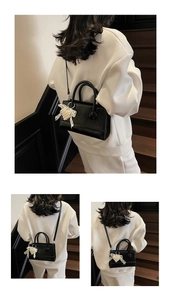 Close-up of black crossbody bag featuring a white lace pearl bow charm and dual handles