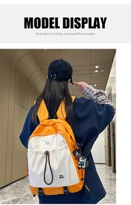 Dettaglio di uno zaino casual arancione e bianco con logo NA NA e ciondolo a forma di orso