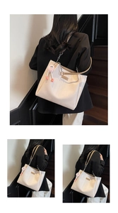 Detail of cream tote bag with metallic chain strap and pink plush charm accessory