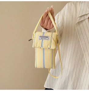Detailed view of yellow and blue striped crossbody phone bag with fabric logo tag