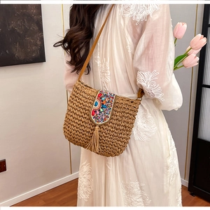 Detail of bohemian straw crossbody bag with ethnic sequins and long tassel fringe