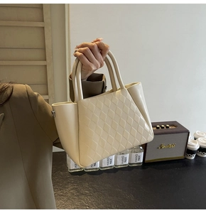 Detail shot of the cream quilted bucket bag showing texture and reinforced dual handles