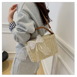 Detail of straw bag with elegant lace bow decoration and pearl accents shown on model