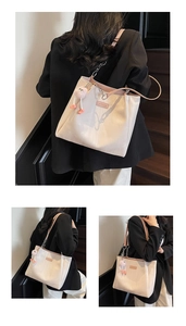 Detail of white tote bag with pink interior and cute plush monster pendant