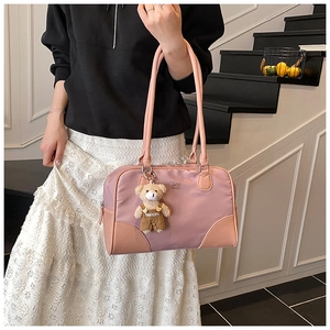 Detail of pink vintage underarm bag with cute teddy bear charm and leather handles