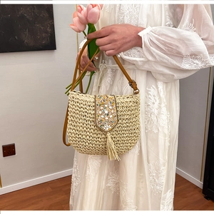 Close-up of bohemian straw bag with floral beadwork, fringe detail and leather strap