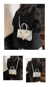 Detail of silver crossbody bag with pearl bow charm and detachable shoulder strap