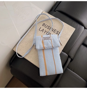 Close-up of the blue and white striped fabric phone bag with Fashion Instinct label detail
