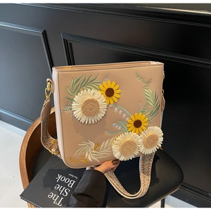Detailed view of sunflower embroidery and wide geometric strap on beige crossbody bag