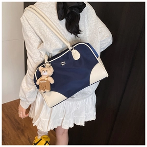 Retro underarm bag in navy and cream with a plush bear charm shown on model