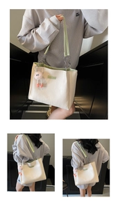 Detail of cream tote bag with green leather chain handle and pink plush monster charm