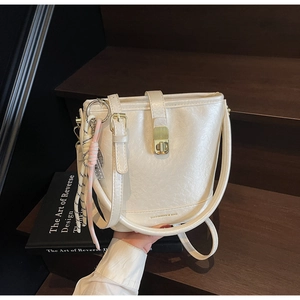 Détail du sac seau blanc cassé avec texture grainée et fermoir rotatif doré élégant