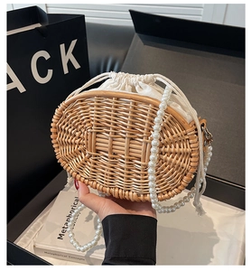 Detail of woven rattan bag featuring white drawstring liner and long pearl shoulder strap