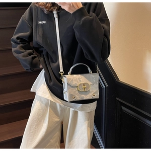 Detail shot of grey marble pattern handbag with a golden oval buckle on stairs
