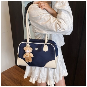 Detail of navy canvas shoulder bag with cream trim and cute bear plush charm accessory