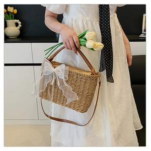 Detail of hand-woven straw bag featuring a white lace bow and elegant pearl accents