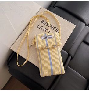 Detailed view of the yellow and white striped crossbody phone bag with FASHION label