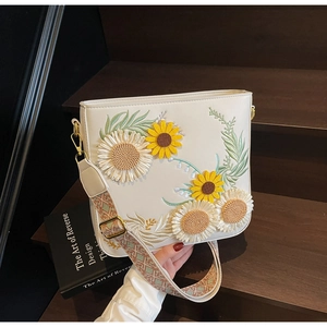 Detail of sunflower and daisy embroidery on a white bucket bag with bohemian strap