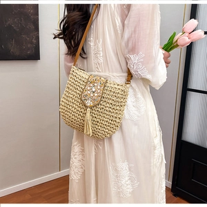 Close-up of bohemian straw crossbody bag with detailed ethnic embroidery and beaded tassels