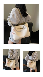 Detail of large off-white tote bag with olive straps and pink plush pendant