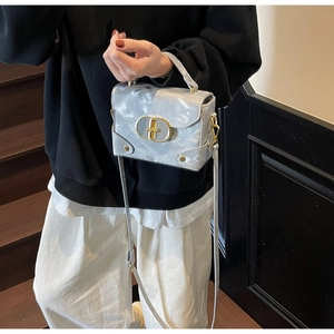 Detail view of small grey marble pattern handbag with golden metal CD logo clasp and strap