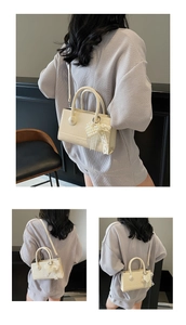 Detail of minimalist beige PU leather crossbody bag with pearl bow charm and top handle
